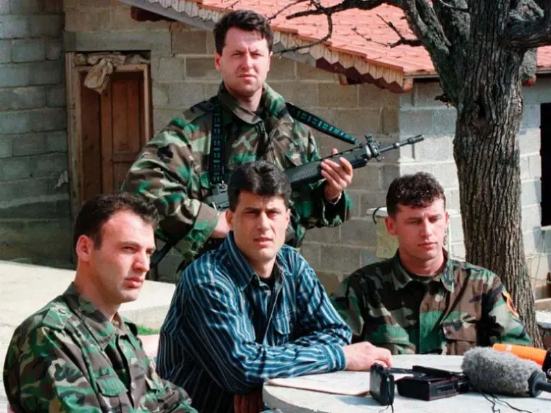 Haşim Taçi (ortada) 13 Mart 1999'da Kosova Savaşı sırasında Kosova'nın orta kesimindeki gizli bir sığınakta düzenlenen basın toplantısında.
Süleyman Selimi (En solda oturan) UÇK Genel Komutanıdır. Recep Selimi (En sağda oturan) UÇK kurmaylarından biri olarak tanınmıştır,
Kadri Veseli (Arkadaki silahlı) ise "Çeliku" kod adıyla o dönemki UÇK'nın Bölge Komutanı ve istihbarat şefidir.