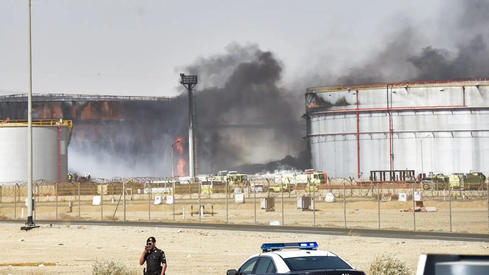 Suudi Arabistan'ın Cidde kentindeki Saudi Aramco petrol tesisinde çıkan yangını itfaiyeciler söndürürken bir polis memuru nöbet tutuyor. (26 Mart 2022)
Husiler, 25 Temmuz 2026'da Cizan ve Yanbu'daki Aramco rafinerilerine saldırdı; bu saldırı, Husilerin 2022'den bu yana Suudi petrol altyapısına yönelik ilk doğrudan saldırısıydı.